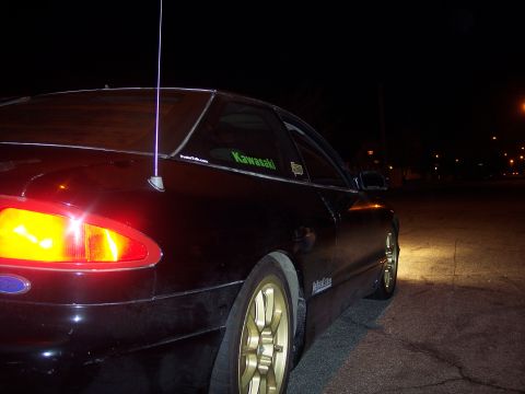 1995 Ford Probe - Rear view of a black 1995 Ford Probe coupe with gold rims parked at night.