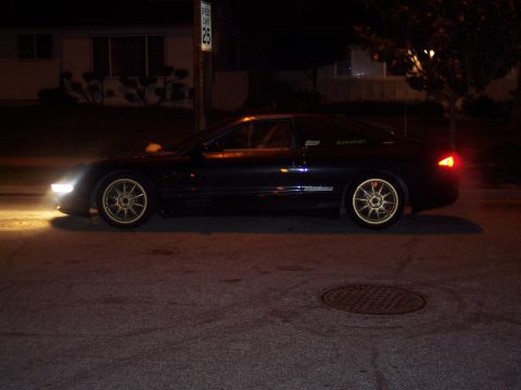 1995 Ford Probe - A black coupe with aftermarket wheels is parked on a street at night, with a speed limit sign visible.
