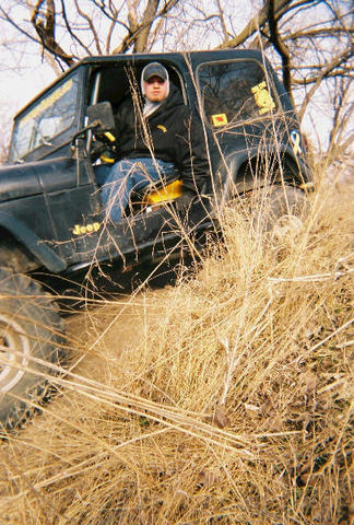 1981 Jeep CJ7 - A driver sits in a black 1981 Jeep CJ7 as it navigates through tall, dry grass.