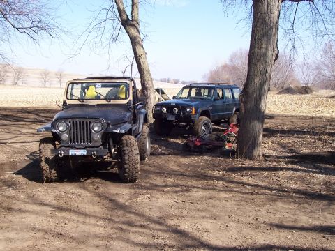 1981 Jeep CJ7 - A black Jeep CJ-5 with a yellow interior is parked in a dirt lot next to a dark SUV.