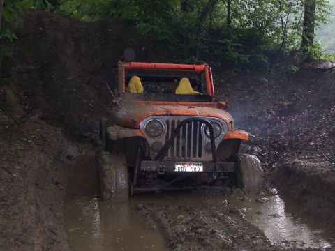 1981 Jeep CJ7 - This 1981 Jeep CJ7 navigates a muddy off-road trail, its front end submerged in water and mud.