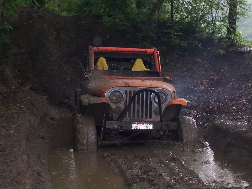 Orange Jeep CJ7 stuck in mud, front view. License plate reads DDV 209
