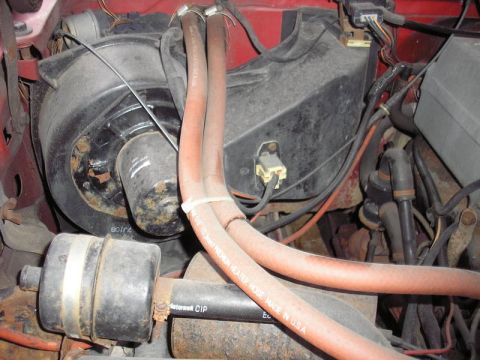 1991 Ford Bronco - Close-up view of the heater core and blower motor assembly, showing orange heater hoses and associated wiring.