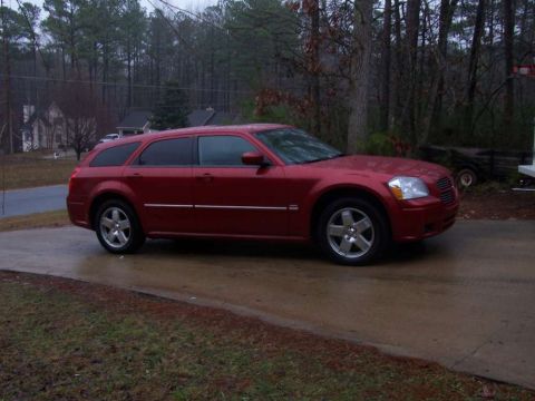 1979 Ford F-150 - A red station wagon is parked on a wet driveway with trees in the background.
