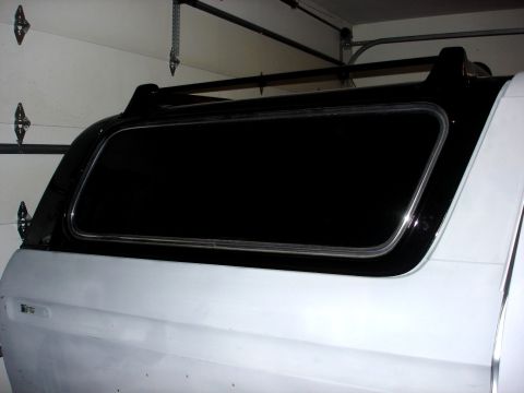 1979 Ford Bronco - Rear side view of a white 1979 Ford Bronco a black camper shell and roof rack.