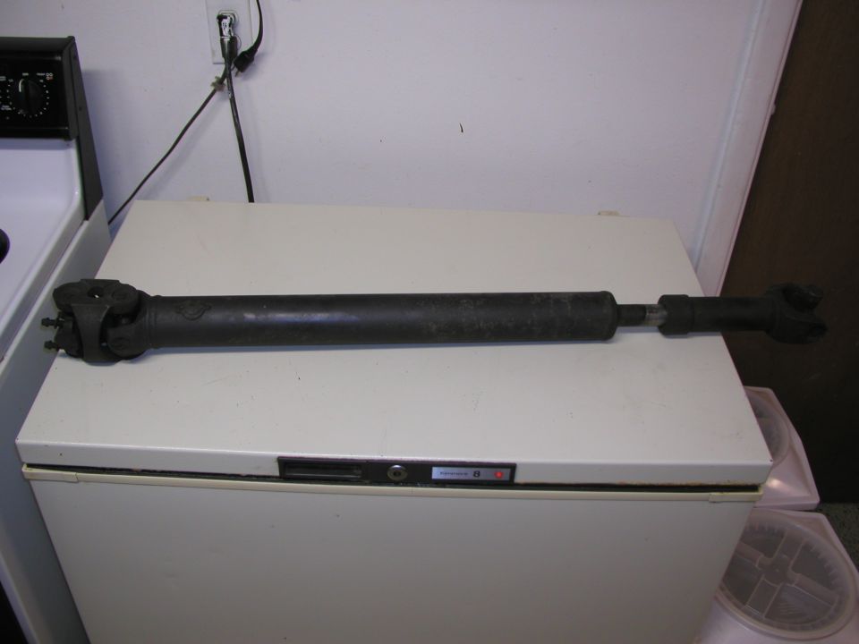 Driveshaft with U-joints on both ends, resting on a white chest freezer