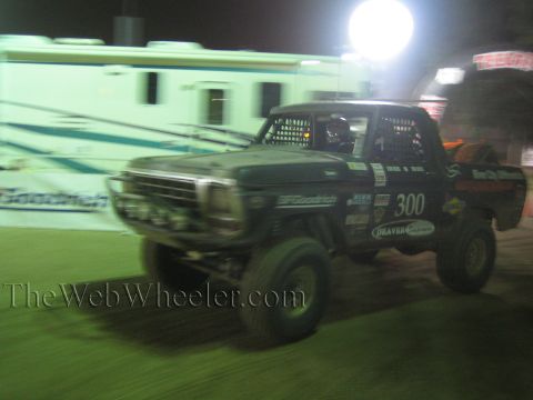 Green vintage Ford off-road race truck number 300 at speed at night