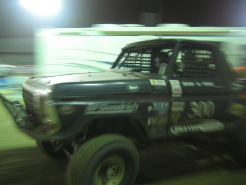 Black off-road race truck number 300 with BFGoodrich decals moving at night, motion blur