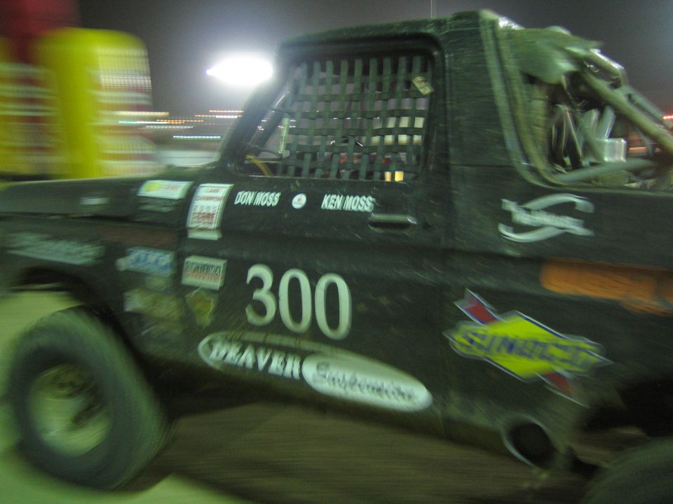 Dust-covered black race truck number 300 with Sunoco and Deaver decals at night