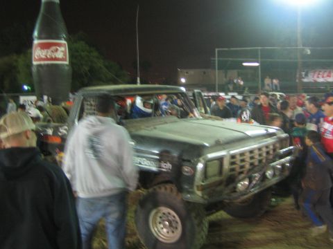 Front three-quarter of dusty Ford race truck with BFGoodrich tires in a night crowd