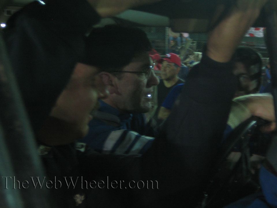 Close-up of a smiling bespectacled man inside a race vehicle at night