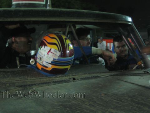Colorful sticker-covered racing helmet on a dusty race truck dash at night