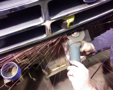 1995 Ford Bronco - A person is modifying the vehicle's grille with an angle grinder, creating a shower of sparks.