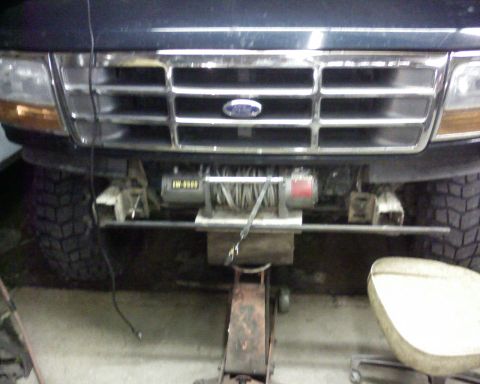 1995 Ford Bronco - Front view of a dark blue Ford Bronco, showing its grille, headlights, and an aftermarket winch.