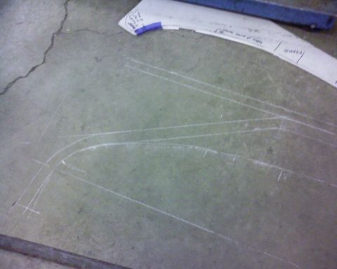 1995 Ford Bronco - Photograph of a garage floor with chalk reference lines and a paper template, not a technical document.
