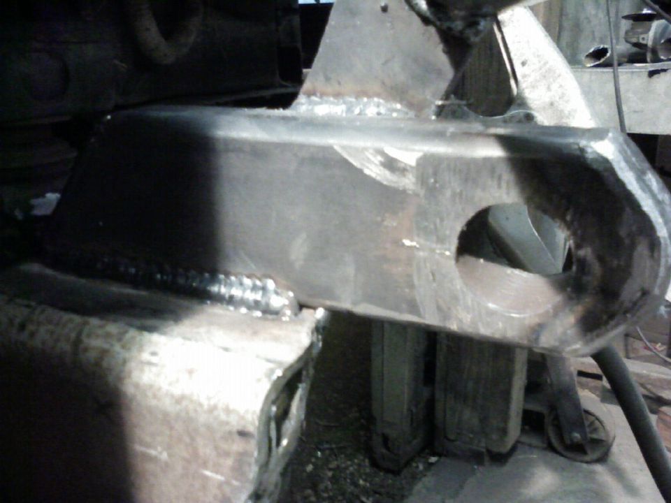 Welded metal bracket with a large circular hole, showing rough metal and weld marks