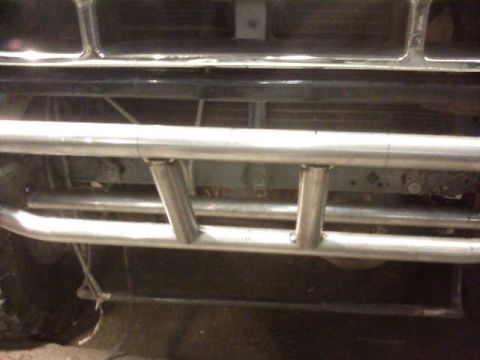 1995 Ford Bronco - Front view of a shop-built two-tier tube bumper in bare weld-finished steel, mounted low across the front of a truck with vertical support…