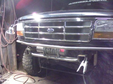 1995 Ford Bronco - Front view of a black Ford Bronco with a winch and custom bumper, showing the grille and headlights.