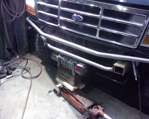 1995 Ford Bronco - Front bumper of a 1995 Ford Bronco shows an installed winch, with a jack and blocks underneath.