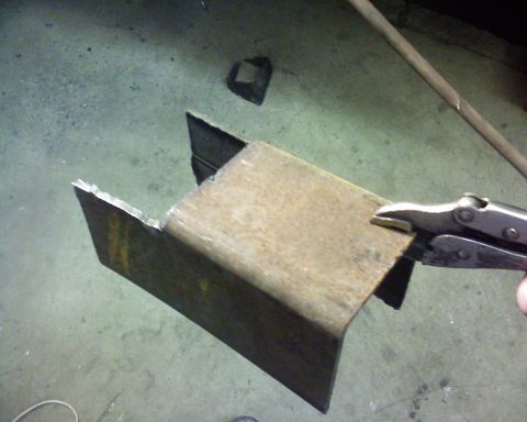 1995 Ford Bronco - A metal bracket is being held by vice grips in a workshop setting.