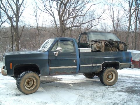 1989 Ford F-250 - Pickup truck carrying a disassembled truck cab and engine components in its bed during winter.