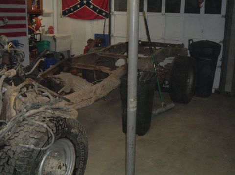 1989 Ford F-250 - A disassembled truck frame sits in a garage, with a Confederate flag and American flag visible in the background.