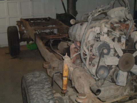 1989 Ford F-250 - A heavily rusted truck chassis and engine are visible in a garage setting.