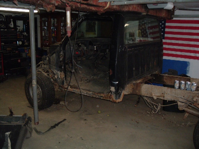 Side view of black pickup truck chassis and cab, missing body panels