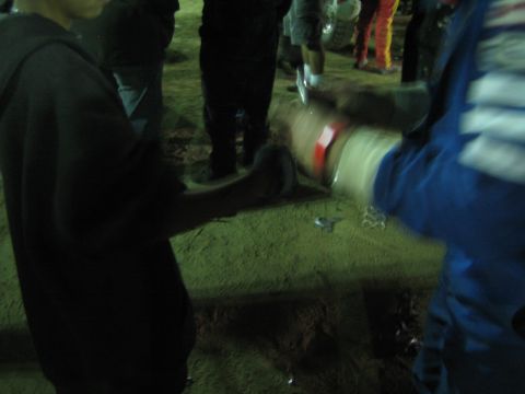Blurry night close-up of two people shaking hands in a dirt crowd