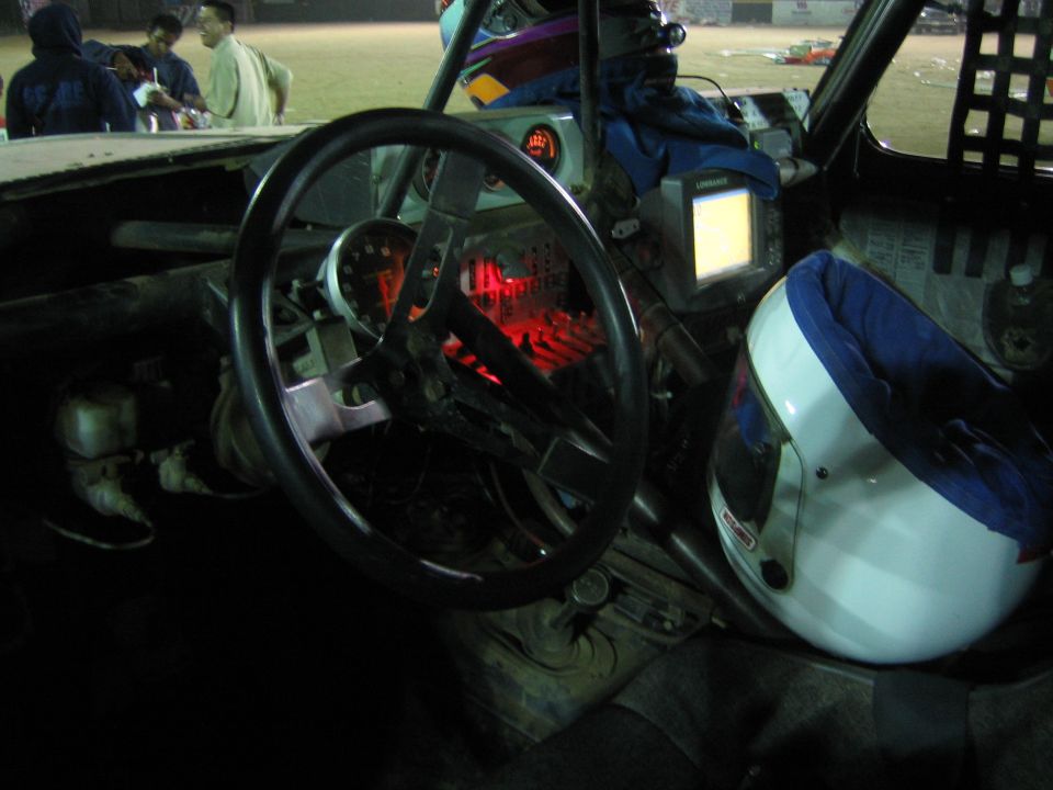 Off-road race cockpit with steering wheel, navigation screen and white helmet