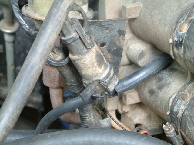 Close-up of engine hoses and connectors, some with dirt and grime