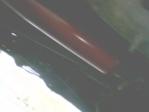 1989 Ford Bronco - Underside view shows vehicle frame and suspension parts, including a red shock absorber.