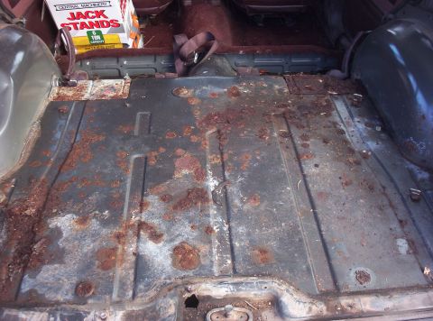 1987 Jeep Cherokee - The cargo area floor shows significant rust and wear, with a box of jack stands visible in the background.