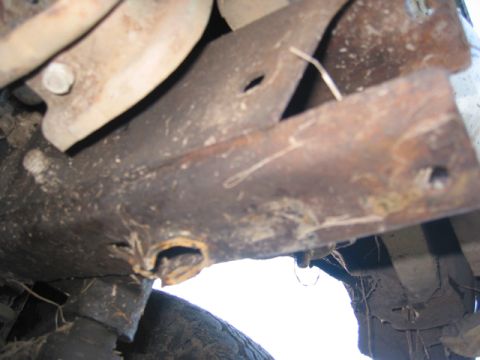 1968 Ford Bronco - Underside view of a vehicle's rusty frame and suspension components, with a tire visible at the bottom.