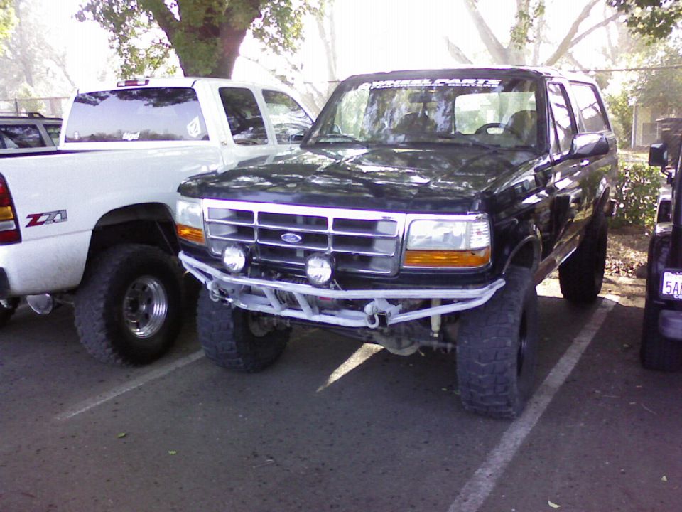 Lifted black Ford Bronco with white tube bumper, winch and mud tires