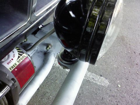 1995 Ford Bronco - Close-up of a winch mounted behind a white-painted tube bumper, with its red "FREE SPOOL" clutch lever decal and spooled steel cable visibl…