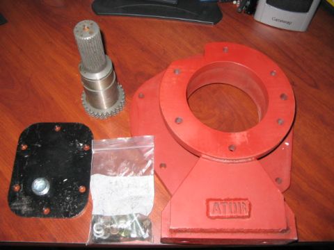 1991 Ford Bronco - Various automotive parts, including a red metal housing and a splined shaft, are laid out on a wooden surface.