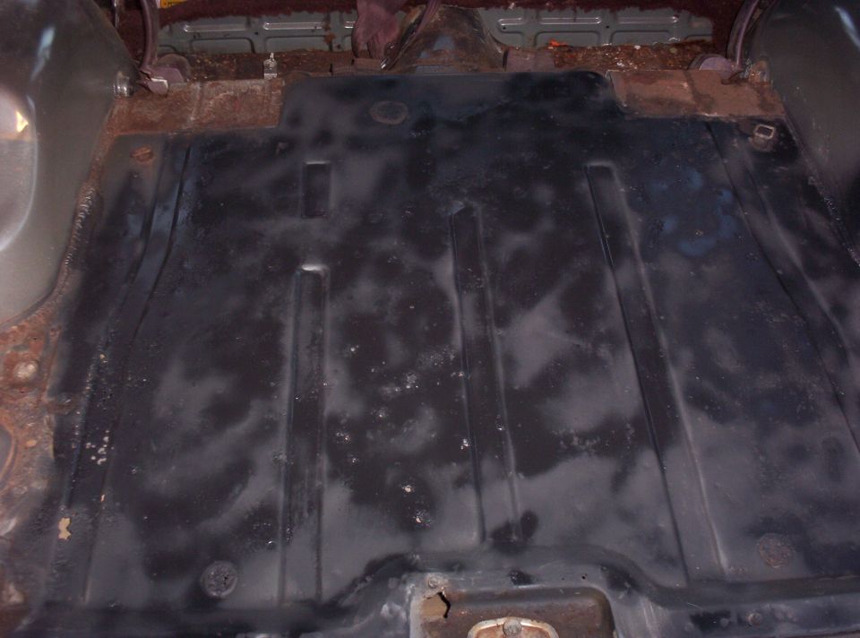 View of a rusty and dirty vehicle floor pan with black coating