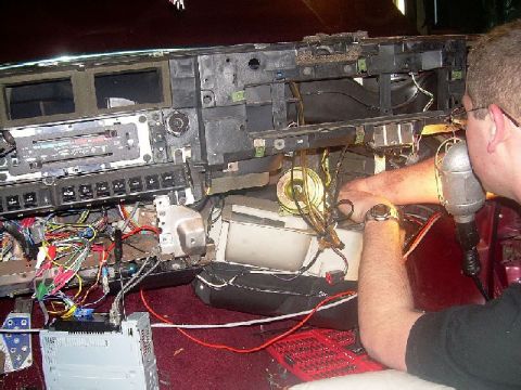 1992 Ford Crown Victoria - A person works on the complex wiring of a car's dashboard, revealing the internal components.