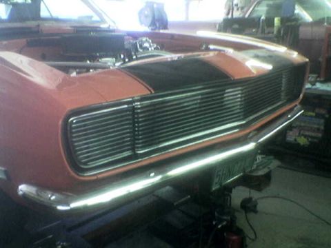 1988 Ford Bronco - Front view of an orange car with black racing stripes and a prominent chrome grille.