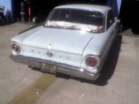 1988 Ford Bronco - Rear view of a pale blue 1963 sedan, showing its distinctive taillights and chrome bumper.