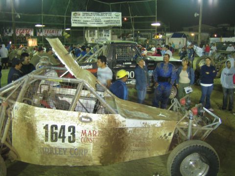 Side view of gold off-road buggy 1643 with people standing around it at night