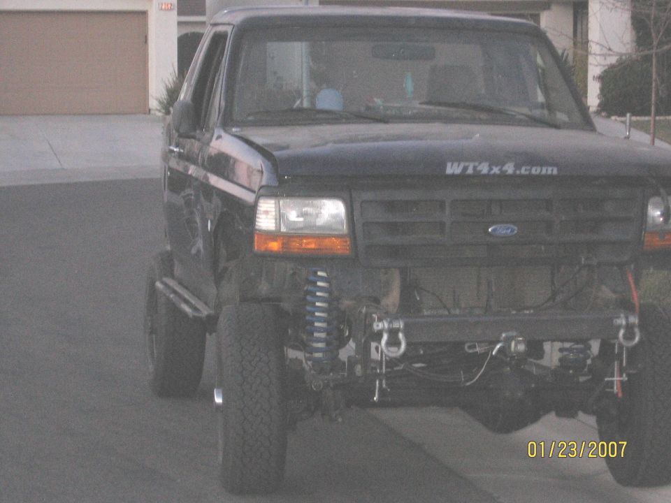 Lifted dark Ford Bronco showing front suspension, blue shocks, winch and WT4x4.com decal