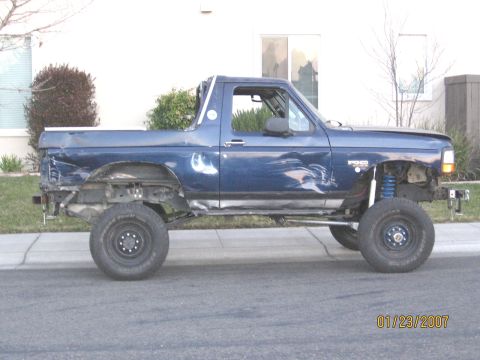 1994 Ford Bronco - This blue Ford Bronco has visible damage and is missing its front fenders and rear bumper.