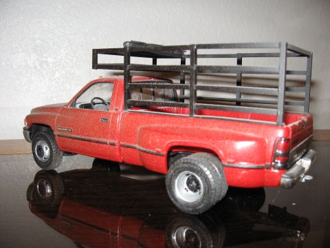 1977 Ford F-150 - A red pickup truck model with a metal rack is displayed on a reflective surface.