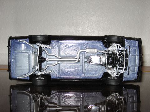 1977 Ford F-150 - The detailed undercarriage of a black model car is displayed, reflecting on a glossy surface.