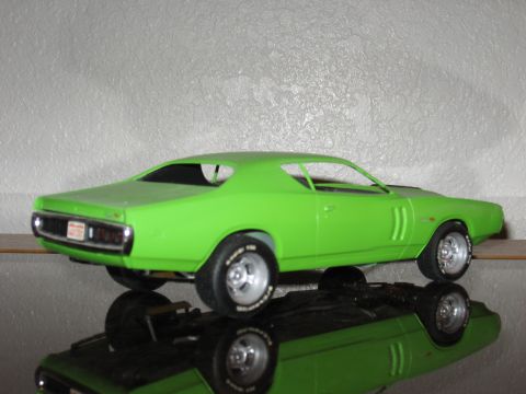 1977 Ford F-150 - A green model car, possibly a 1970s muscle car, sits on a reflective surface.