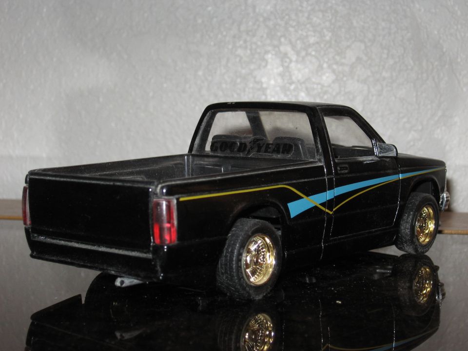 Black model pickup truck with gold wheels and blue/yellow stripe graphics. 'GOOD YEAR' text visible on interior