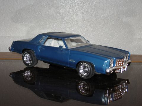 1977 Ford F-150 - A blue model car sits on a reflective surface, casting a shadow. shadow.