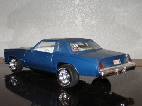 1977 Ford F-150 - A blue model car with a 1977 body style sits on a reflective surface.